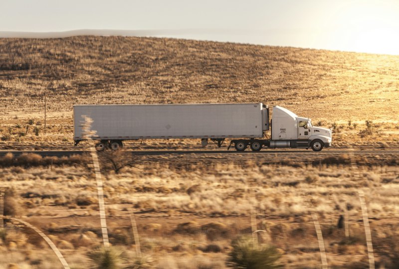 White semi truck hauling a trailer across open country